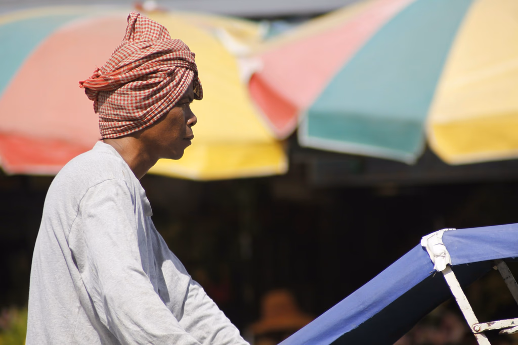 A man in a traditional krama (Cambodian scarf), at his outdoor market stall.