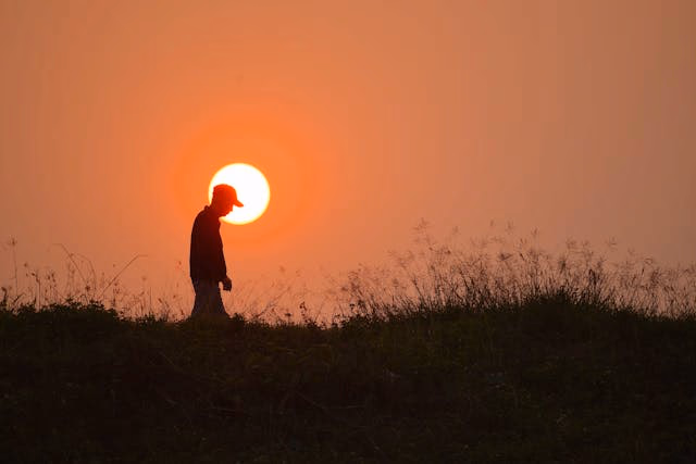 A worker silhouetted against the rising sun.